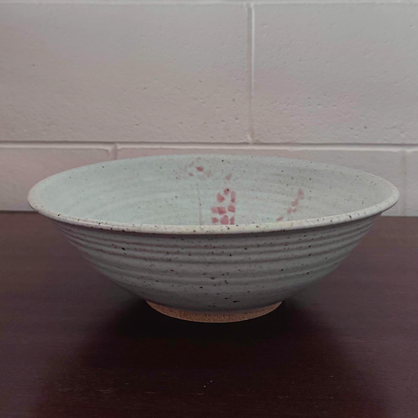 Grey ceramic bowl with speckled glaze and subtle pink accents