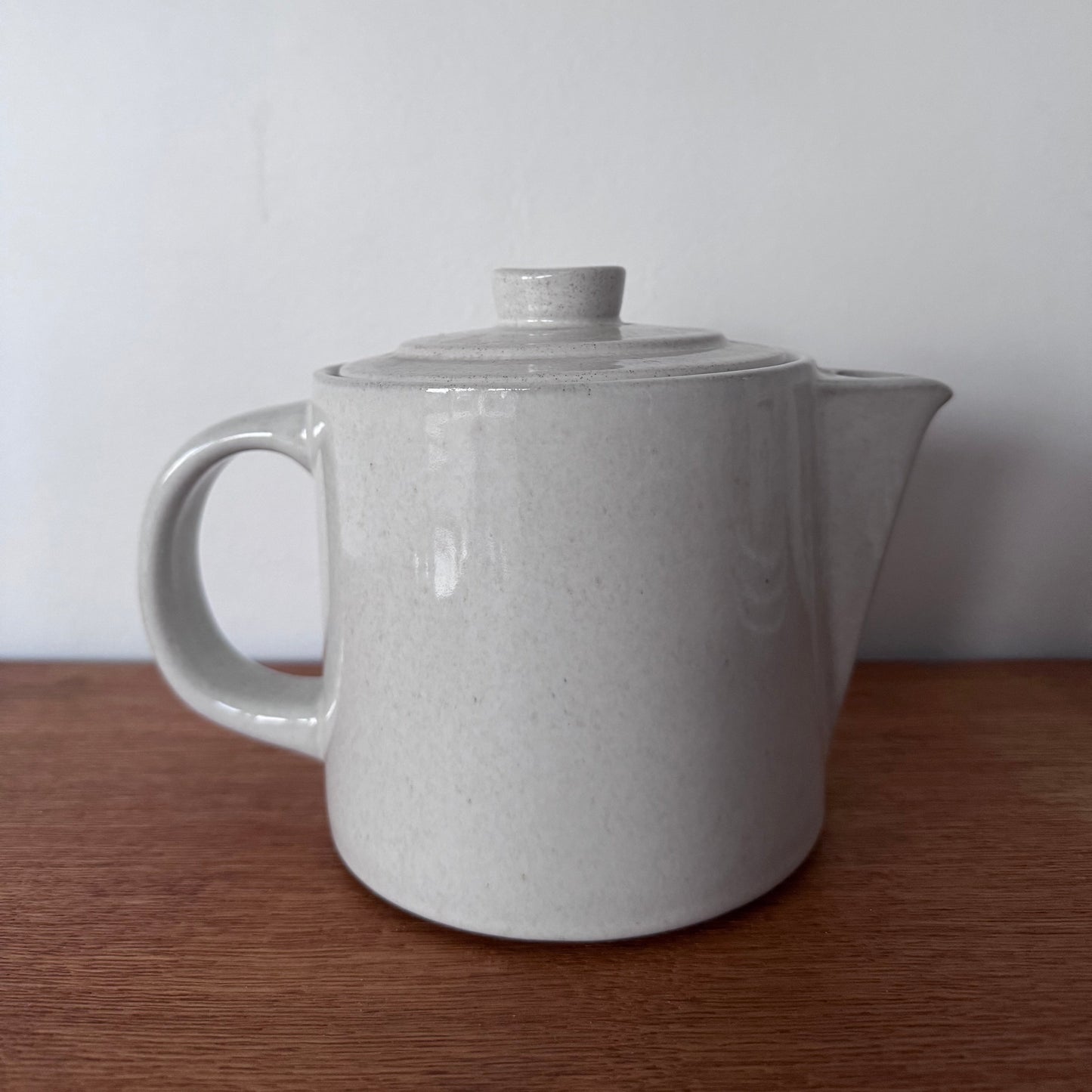 Höganäs Keramik tea set with white ceramic mugs and matching plates, neatly stacked on a wooden surface.