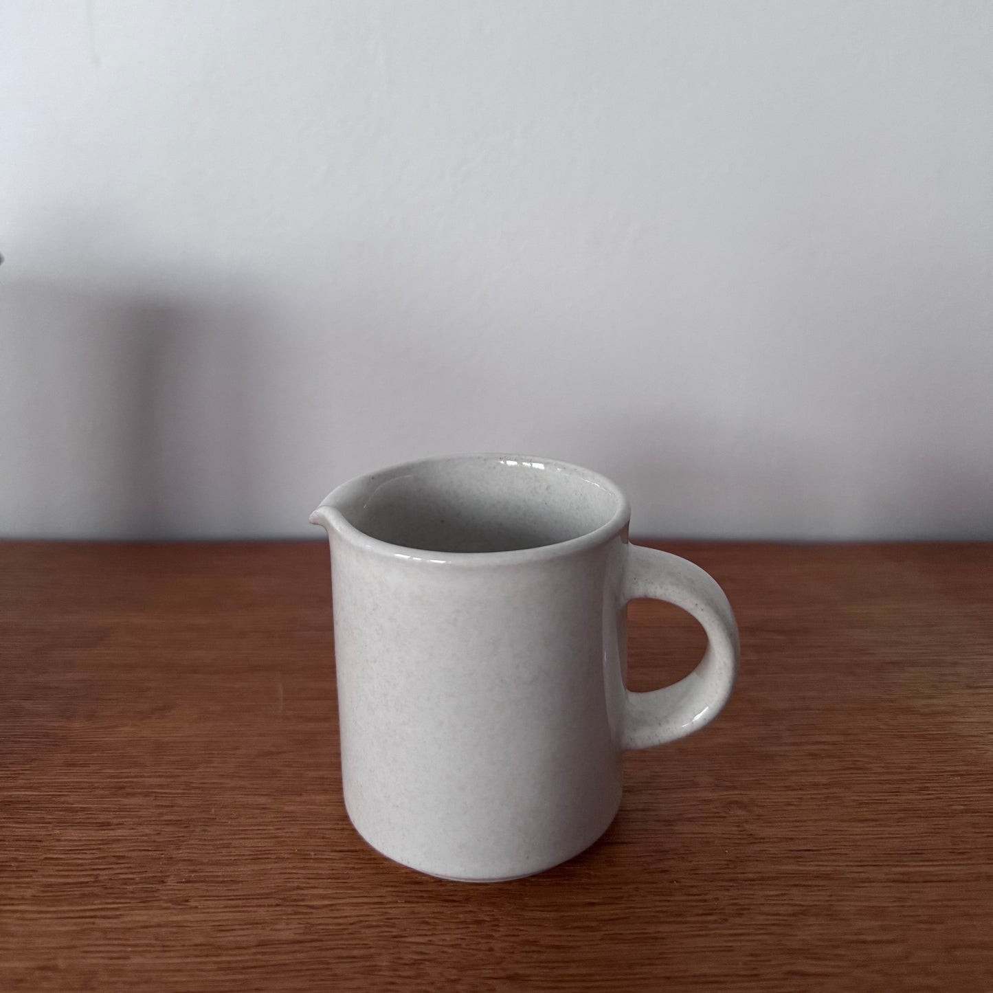 Höganäs Keramik tea set with white ceramic mugs and matching plates, neatly stacked on a wooden surface.