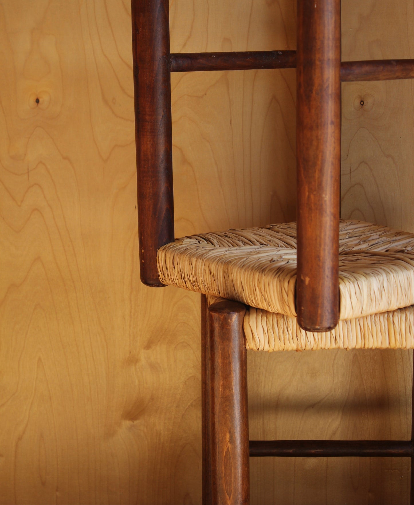 Close-up of a wooden chair with a woven seat on a wooden floor.