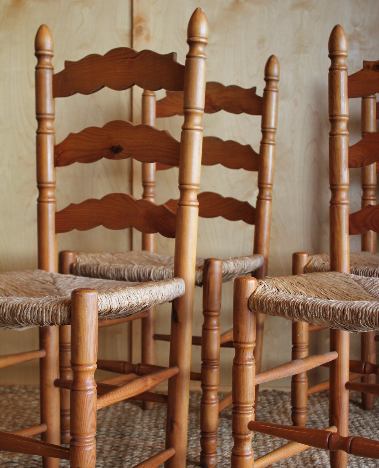 Wooden chair backrests stacked against a textured wall.