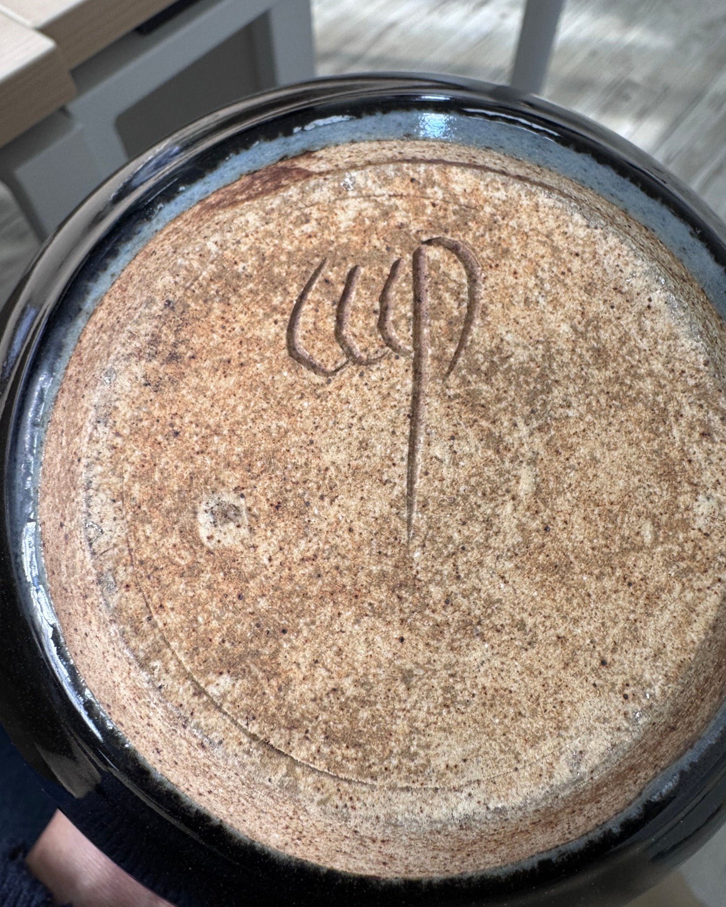 Ceramic dish with a textured surface and engraved symbol, held by a person.
