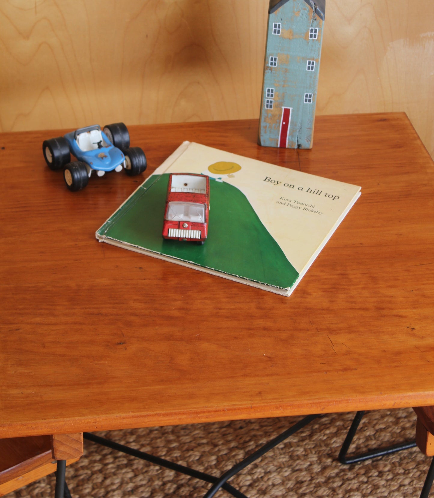 Toy car, house model, and book on a wooden surface