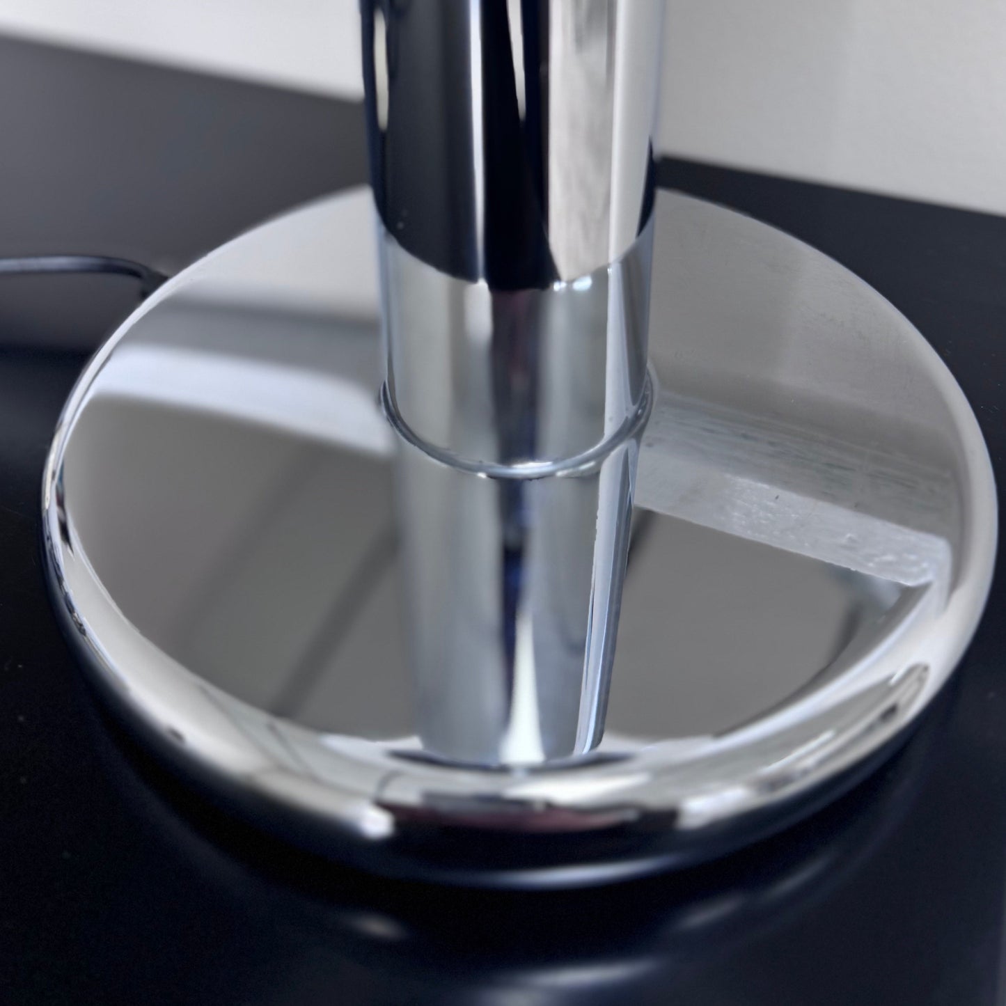 Shiny chrome base and stem of a Targetti Sankey lamp, reflecting its surroundings with a sleek, polished finish