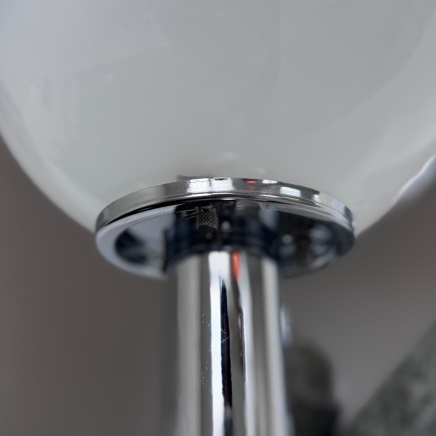 Close-up view of the chrome stem and frosted glass globe of a Targetti Sankey lamp, showing the reflective finish and smooth connection between the base and shade