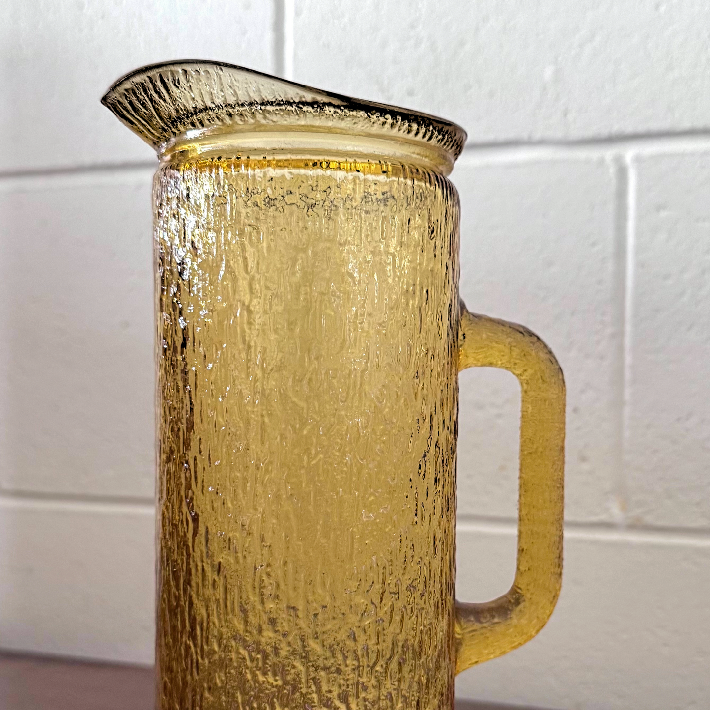 Antique yellow textured glassware featuring a tall-handled pitcher and matching highball glass with an ice-like pattern