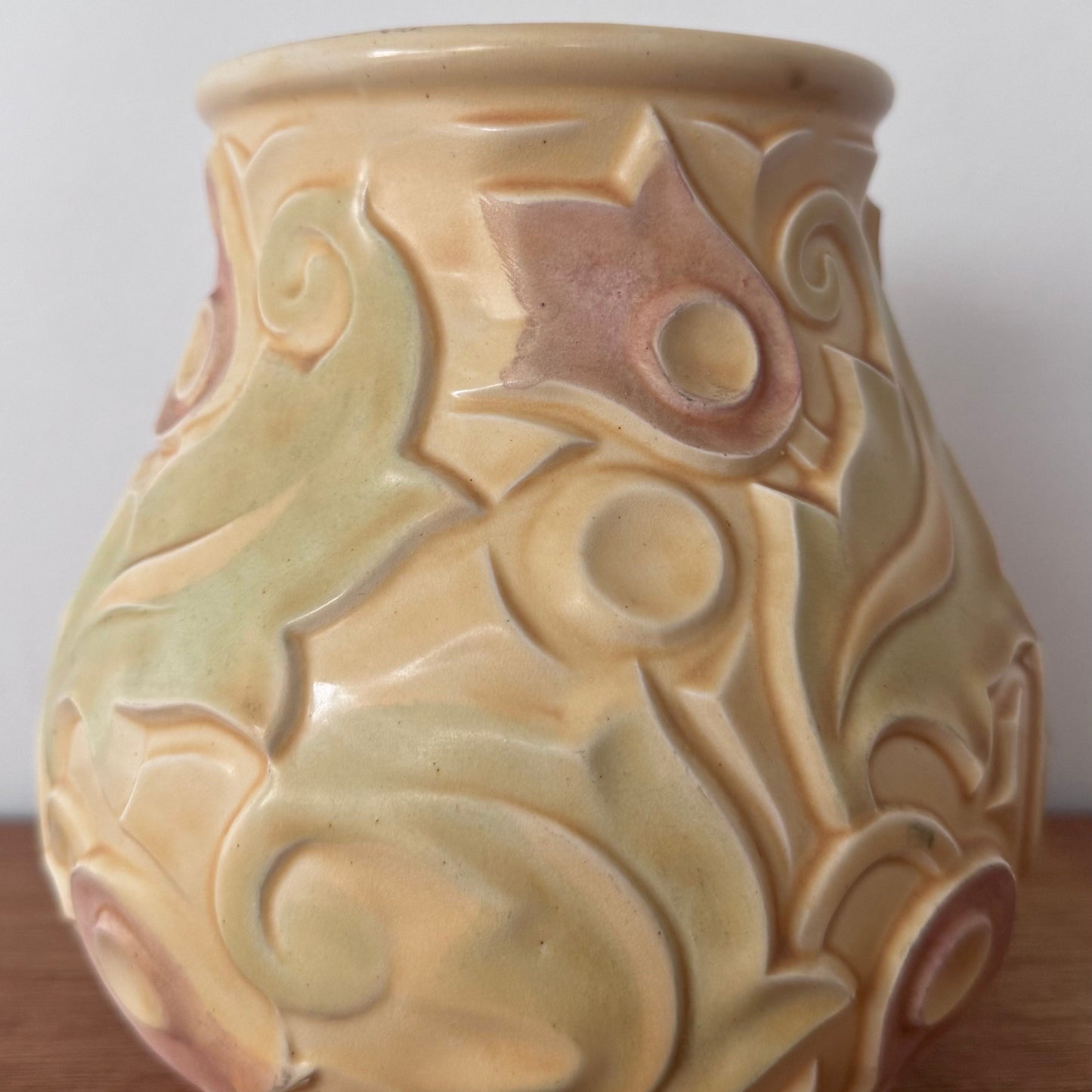 A vintage Wade Heath “Gothic” pattern vase from the UK, featuring embossed swirling floral designs in pastel yellow, green, and soft pink tones with a glossy finish.