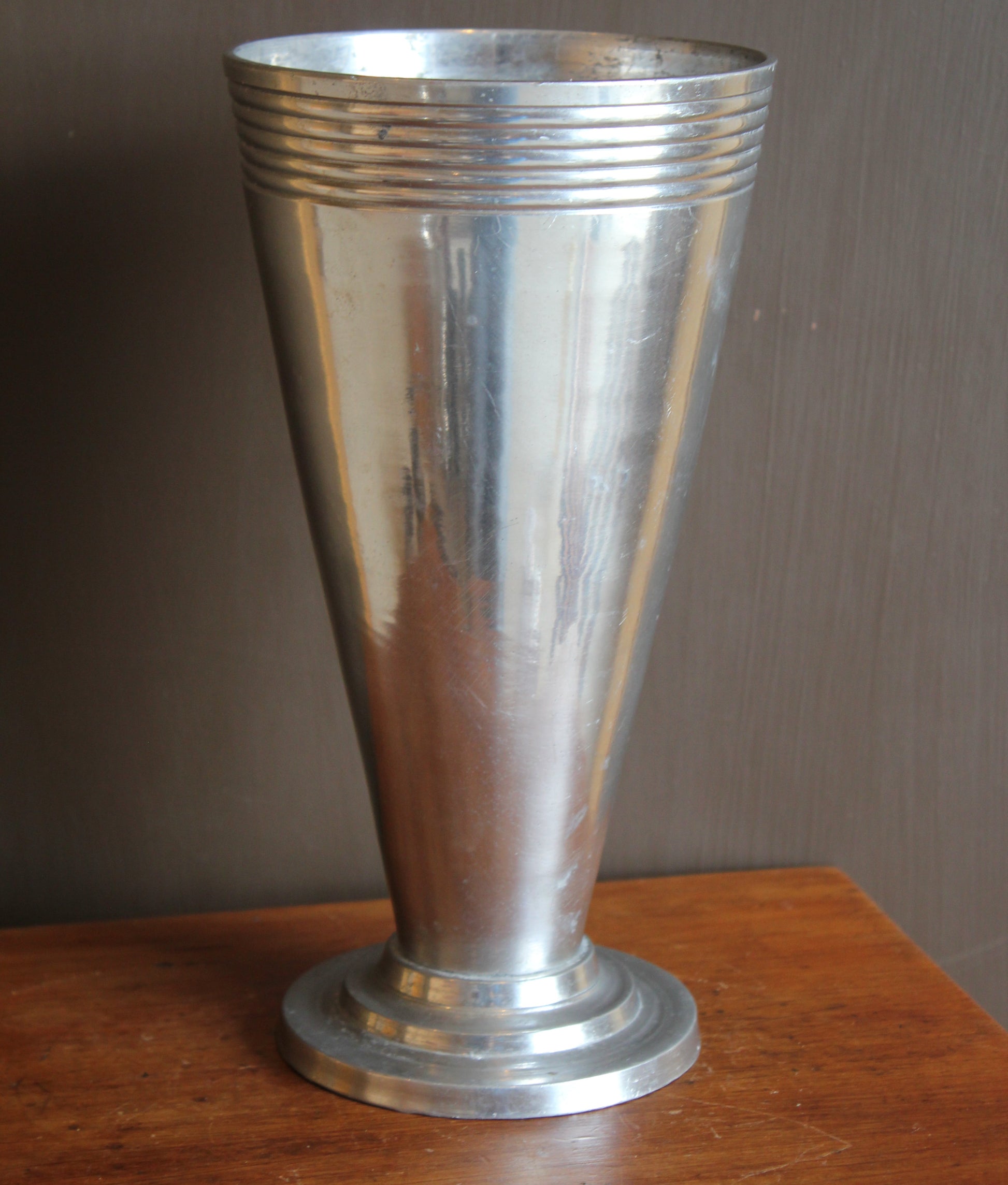 Silver metal vase object on a wooden surface