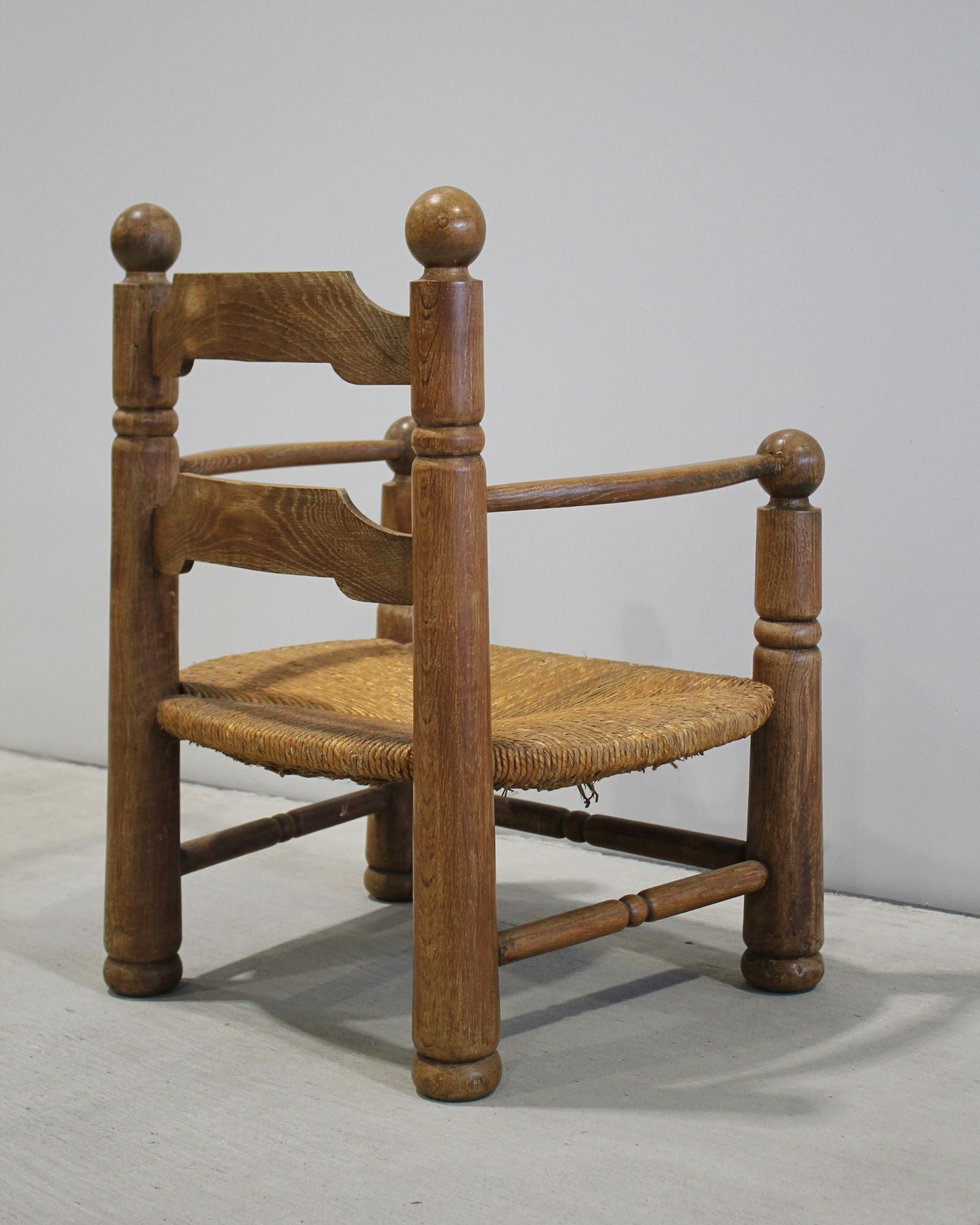 Charles Dudouyt carved timber fireside chair with woven rush seat, mid-century French design, sculptural ball finials, New Zealand
