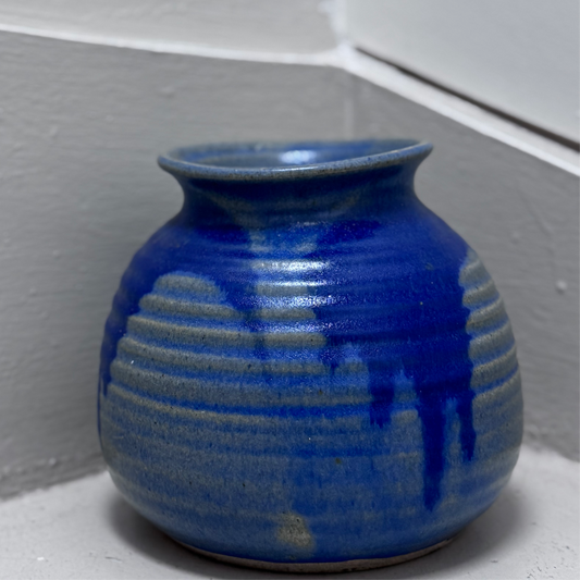 Blue ceramic vase on a white surface with a light gray wall background