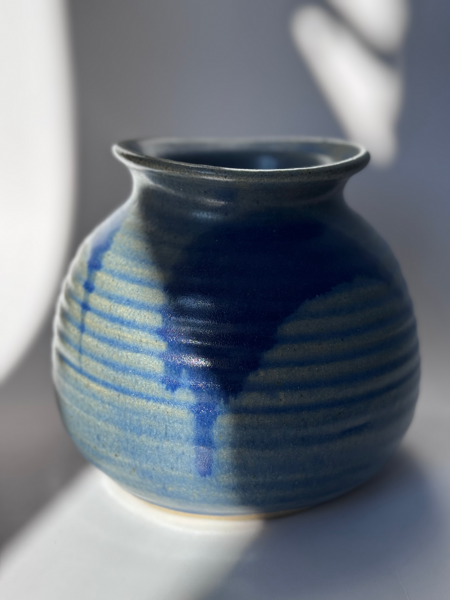 Blue ceramic vase with striped pattern on a gray background