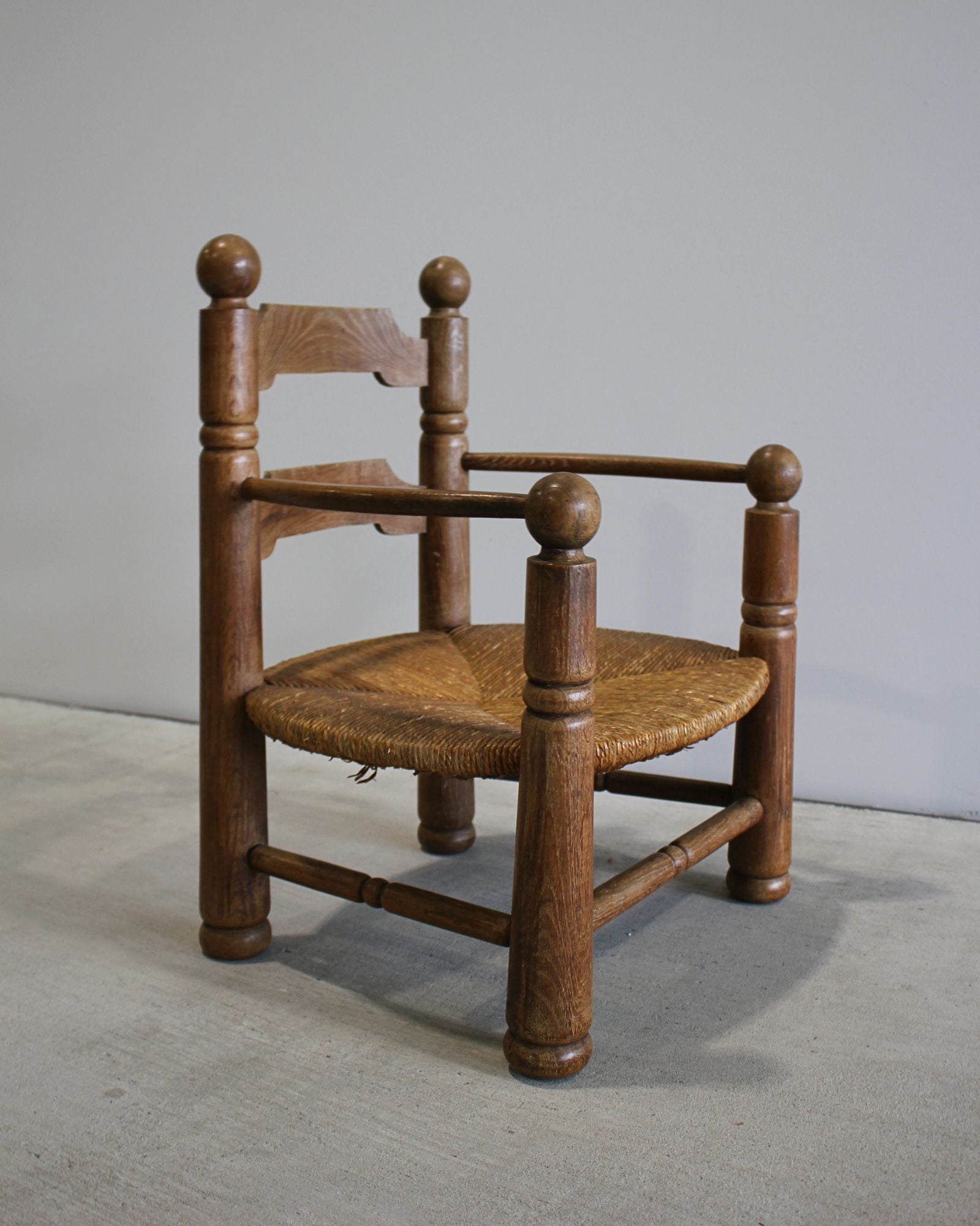 Charles Dudouyt carved timber fireside chair with woven rush seat, mid-century French design, sculptural ball finials, New Zealand
