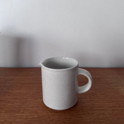 Höganäs Keramik tea set with white ceramic mugs and matching plates, neatly stacked on a wooden surface.