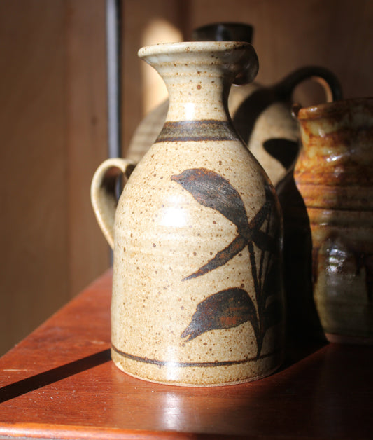 Ceramic vase with leaf design on a wooden surface