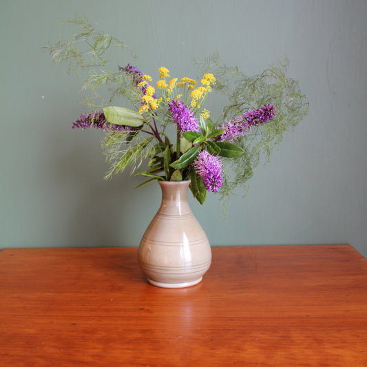 Vase with flowers attached to a wooden surface against a gray wall