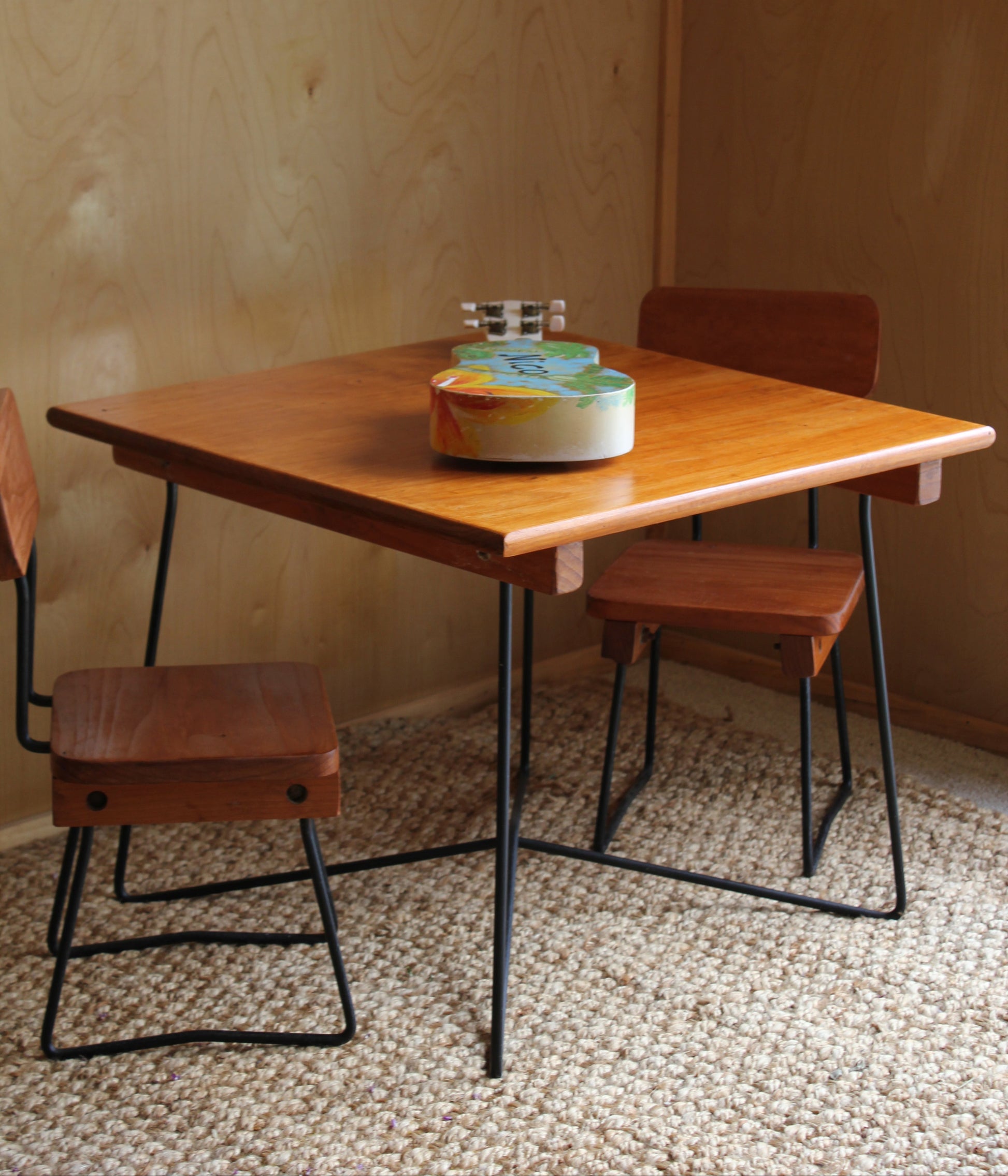 Wooden table with a lamp and chairs against a textured wall.