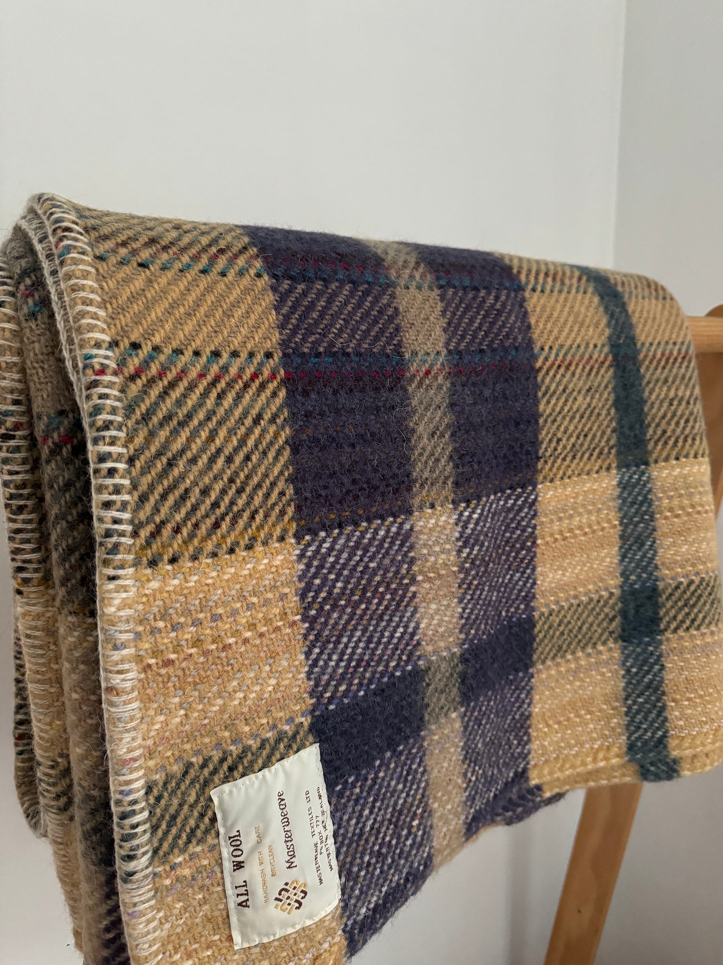 Plaid blanket with a label on a wooden chair against a white wall
