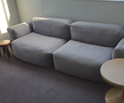 Gray sectional sofa in a room with a lamp and small table.