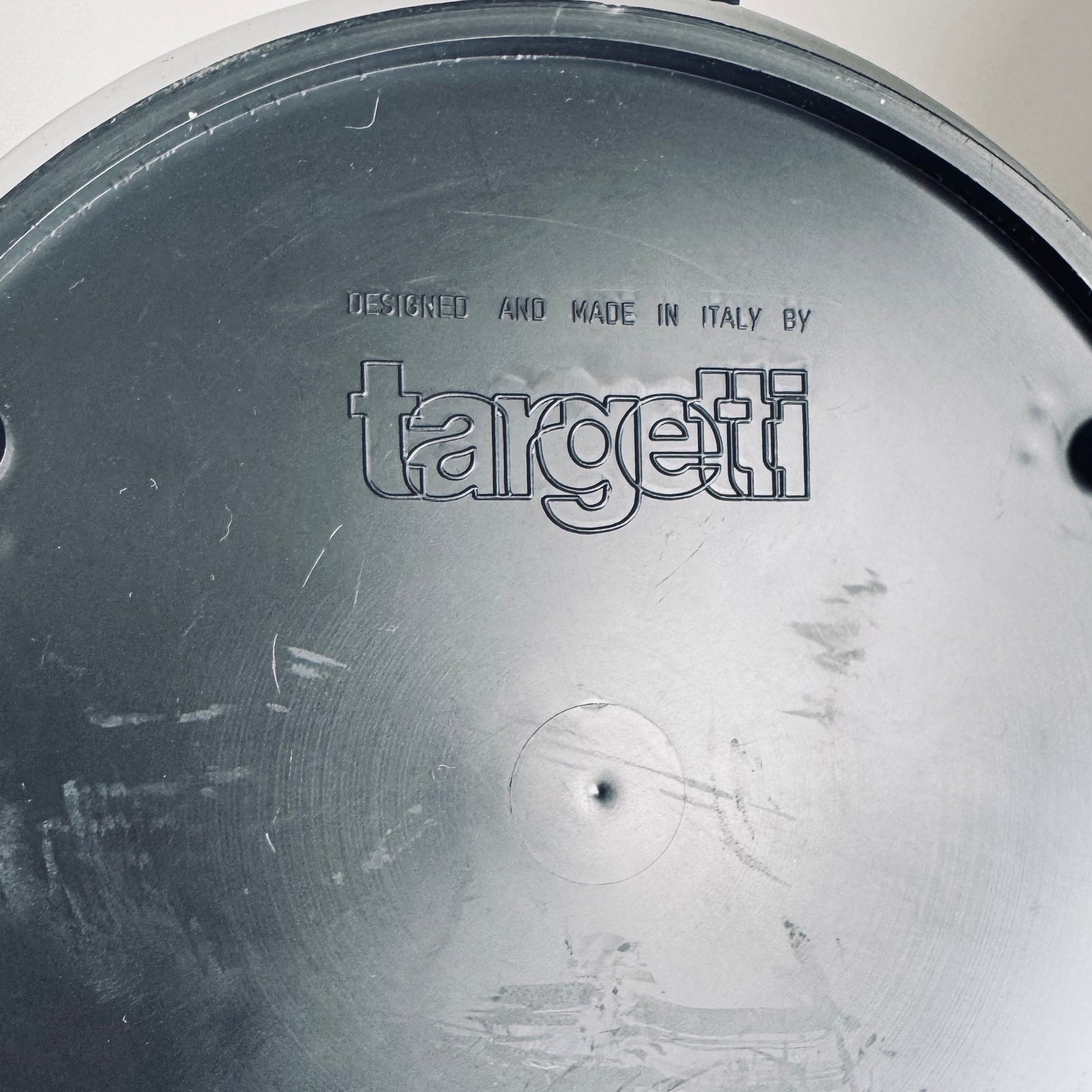 Close-up of the underside of a lamp base showing the embossed text "Designed and Made in Italy by Targetti" on a black surface