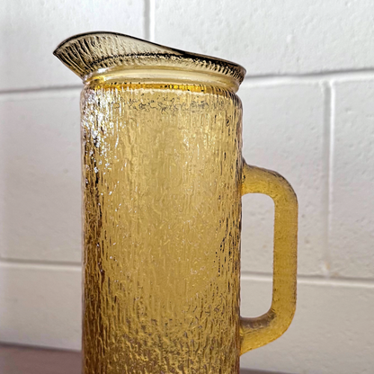 Antique yellow textured glassware featuring a tall-handled pitcher and matching highball glass with an ice-like pattern