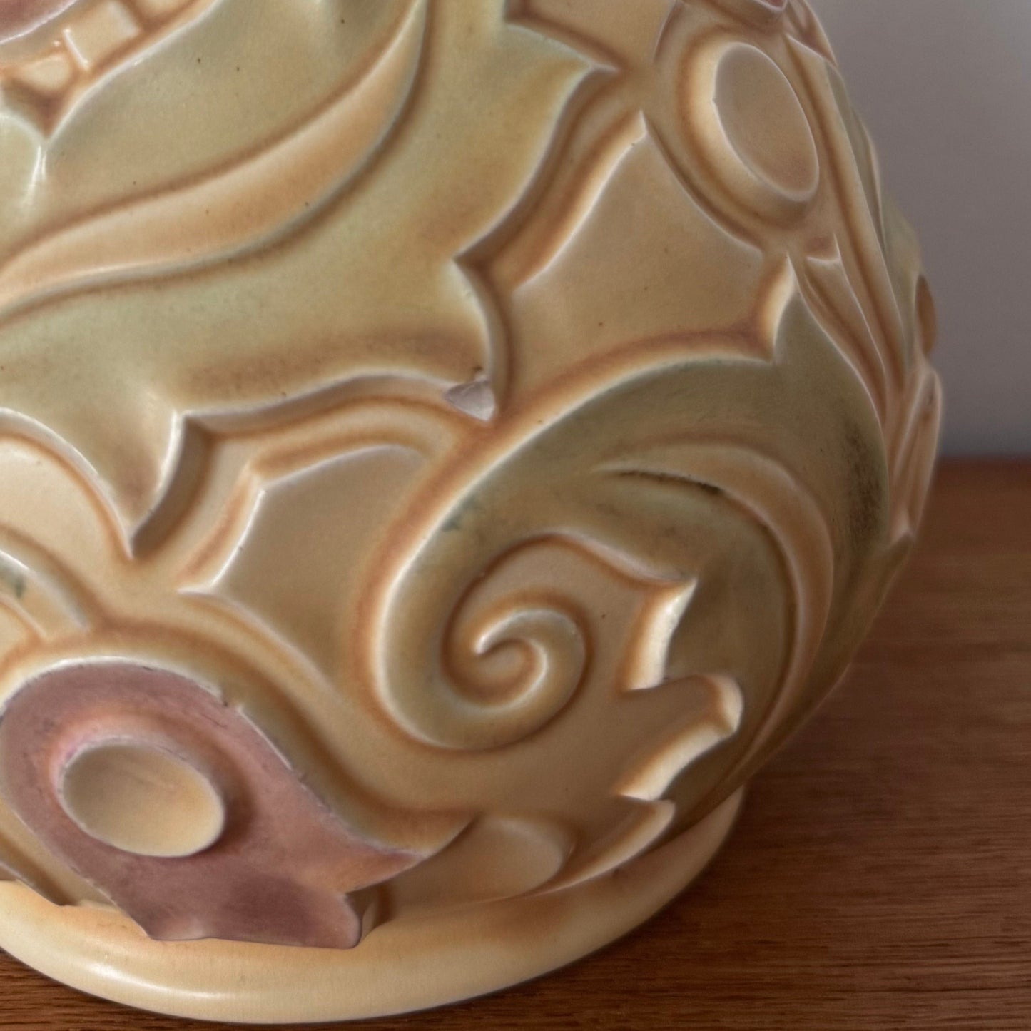 A vintage Wade Heath “Gothic” pattern vase from the UK, featuring embossed swirling floral designs in pastel yellow, green, and soft pink tones with a glossy finish.