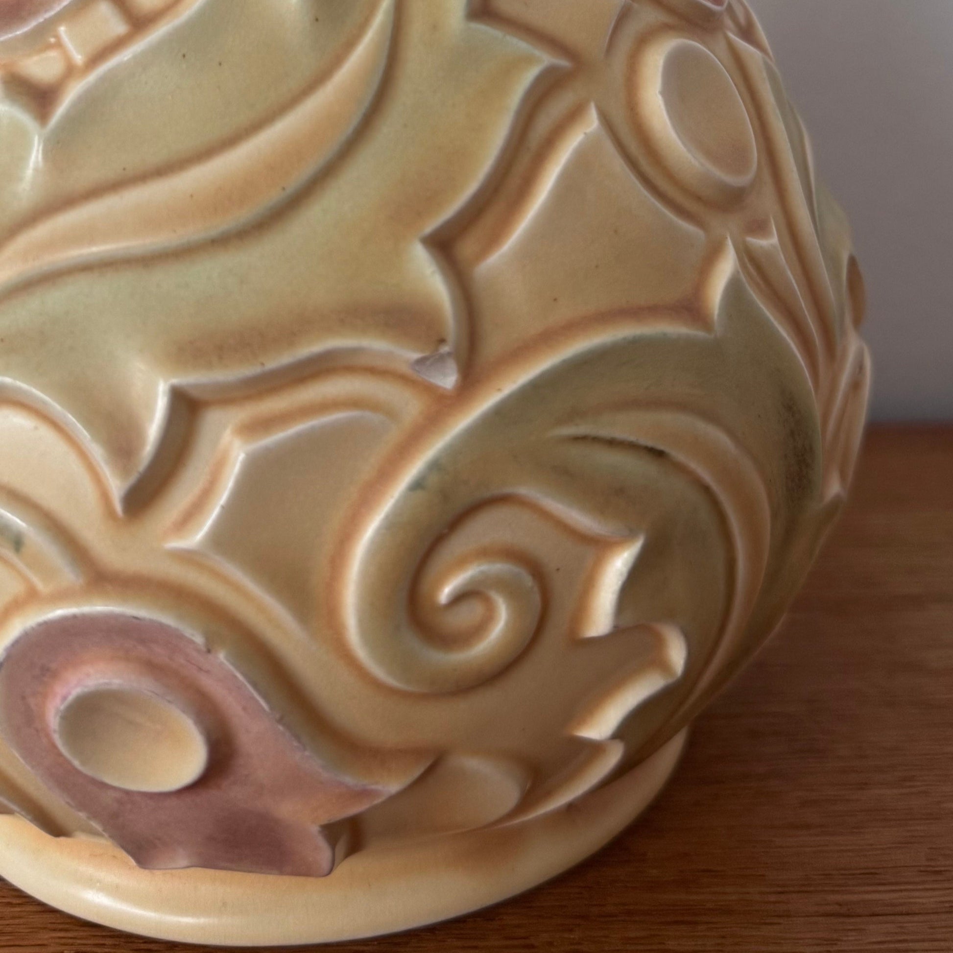 A vintage Wade Heath “Gothic” pattern vase from the UK, featuring embossed swirling floral designs in pastel yellow, green, and soft pink tones with a glossy finish.