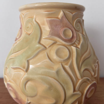 A vintage Wade Heath “Gothic” pattern vase from the UK, featuring embossed swirling floral designs in pastel yellow, green, and soft pink tones with a glossy finish.