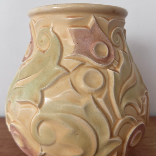 A vintage Wade Heath “Gothic” pattern vase from the UK, featuring embossed swirling floral designs in pastel yellow, green, and soft pink tones with a glossy finish.