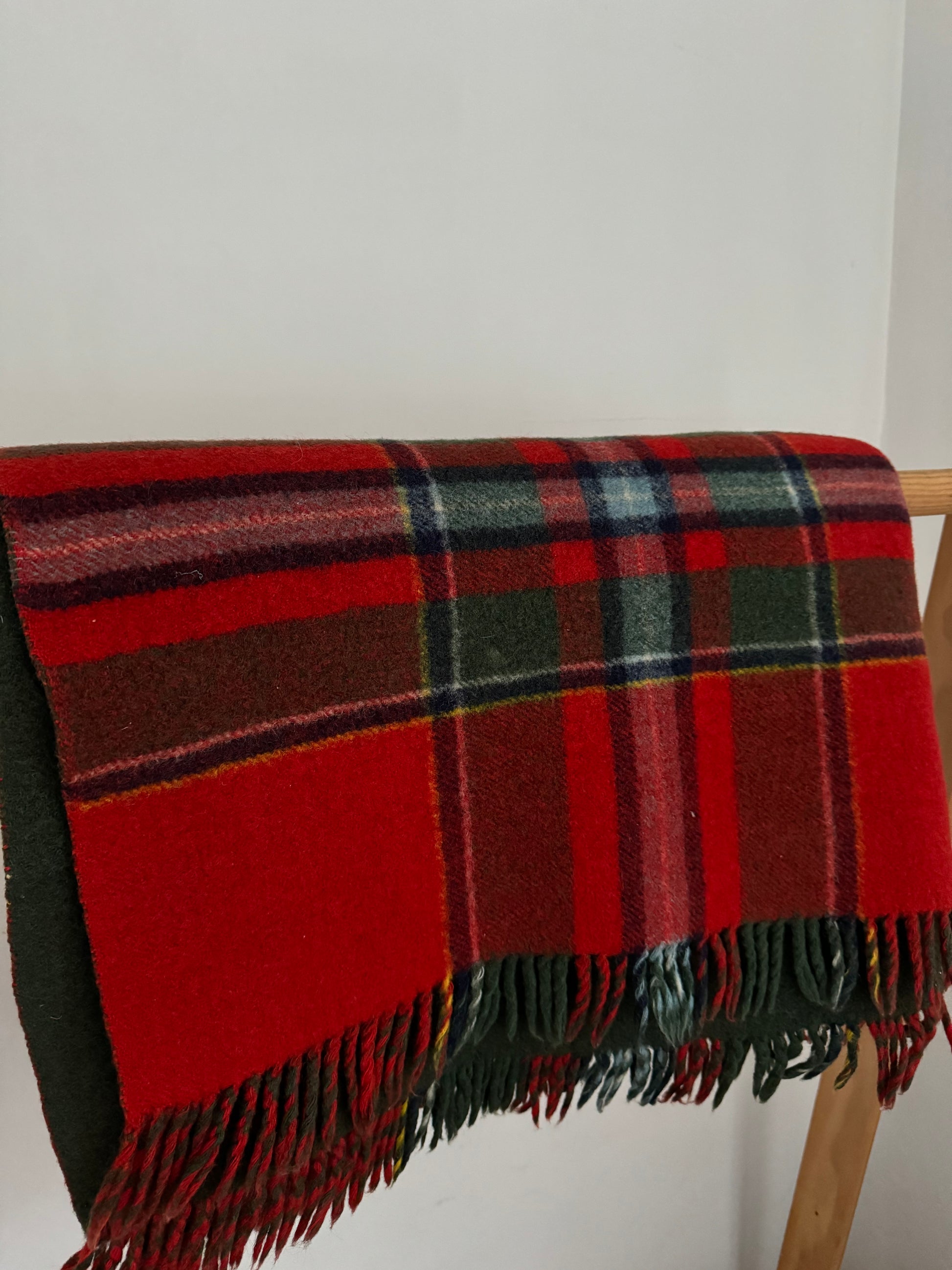 Red and green plaid blanket draped over a chair against a white wall